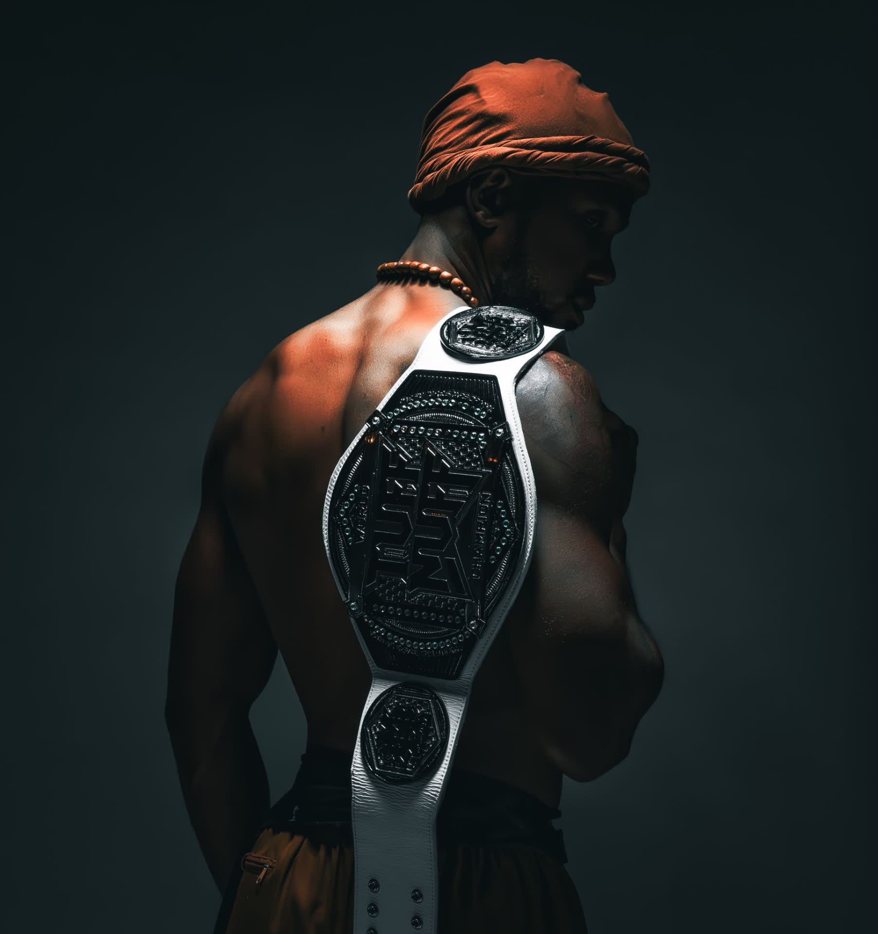 A champion seen from behind with a title belt over his shoulder