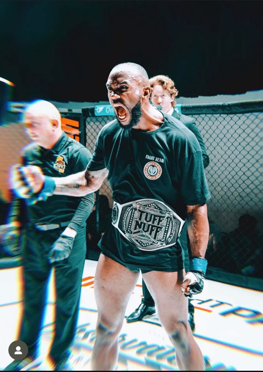Pro MMA fighter Darryl "The Sacred Beast" Walker raising his championship belt in the cage