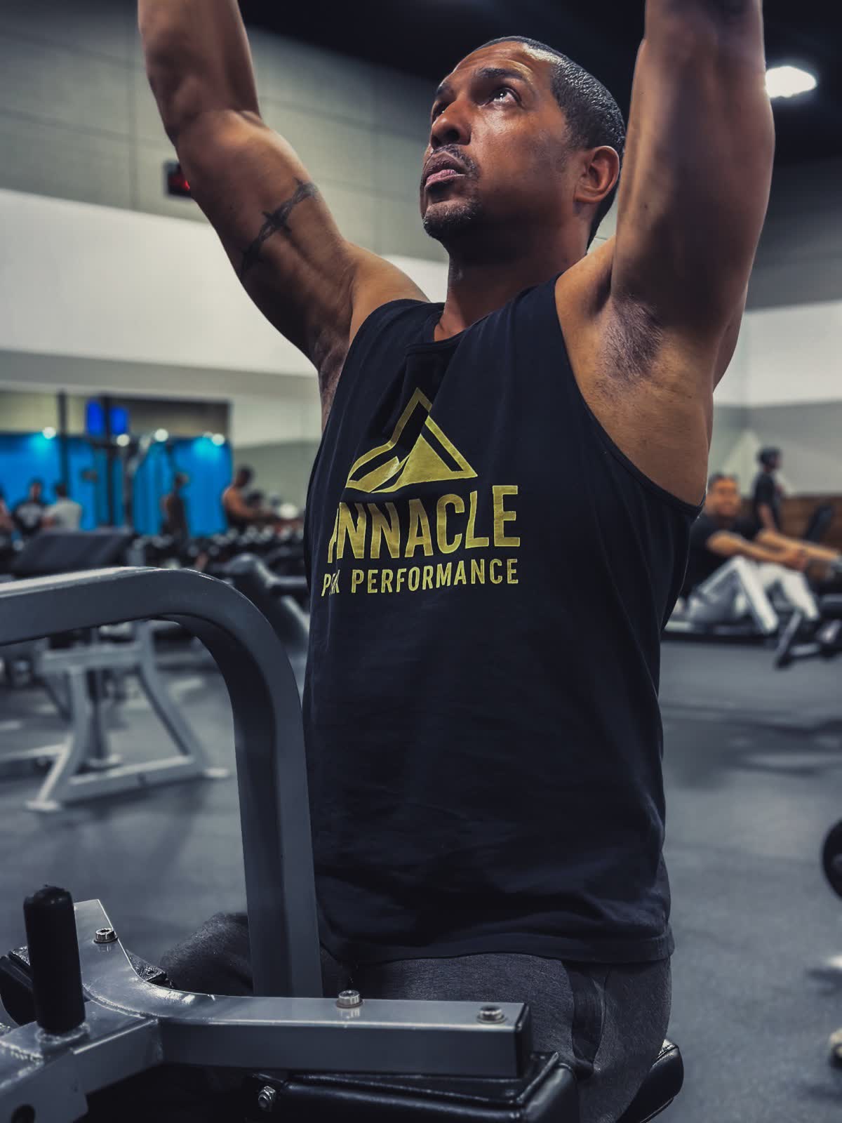 John Hall training, arms overhead at a pull-down machine